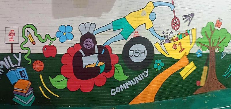 The completed mural, featuring flowers, trees, a yellow brick road, books and the word: Community.