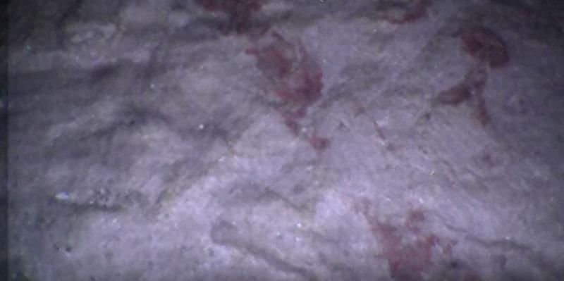 The images shows red symbols or markings on the floor of a small chamber that was discovered.