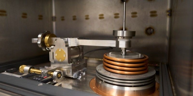 A close-up of the tribometer, showing a metal heated sample stage and contact arm.
