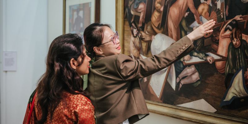 Two visitors to The Stanley and Audrey Burton Gallery discuss a painting close-up.