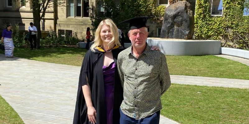 Rachel and Hugh standing together at Rachel's MBA graduation in July 2024.