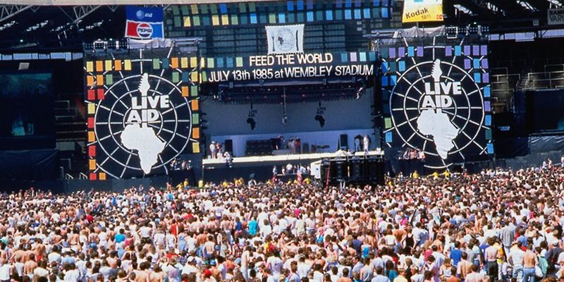 A crowd stand before the stage at Live Aid