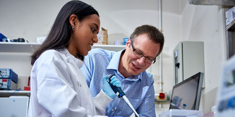 Two bioelectronics academics use a pipette