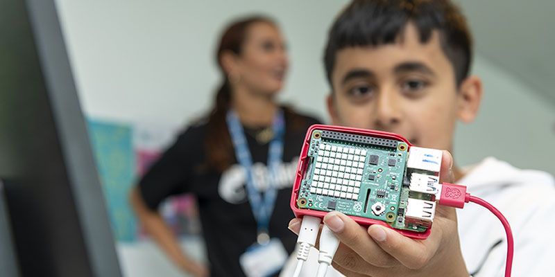 A boy holding a circuit board which features an LED display.