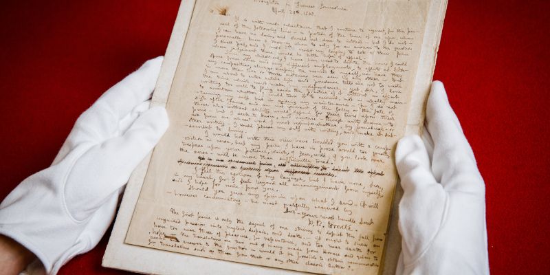 Handwritten letters signed by Branwell Bront&euml; held by hands in white gloves