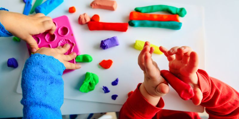 Two young children playing with coloured dough.