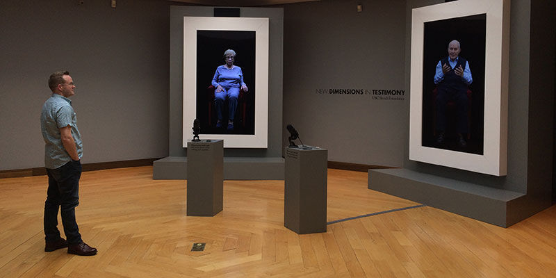A person looking at two large screens in a museum space
