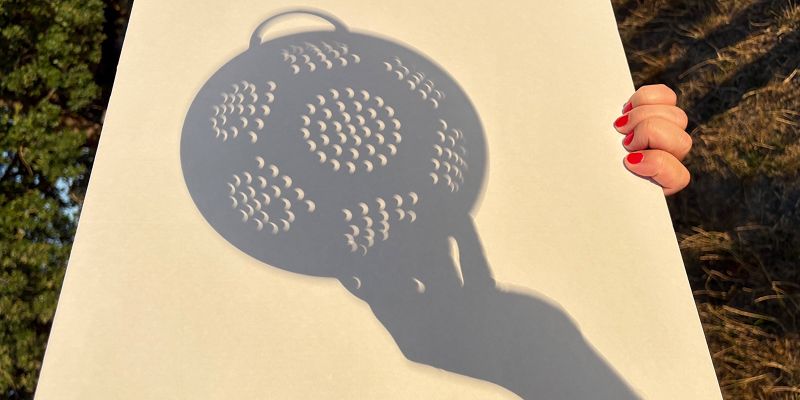 The silhouette of a colander against a sheet of paper
