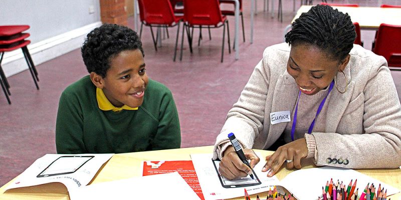 Eunica Beatriz Riquixo teaching a student in a classroom.