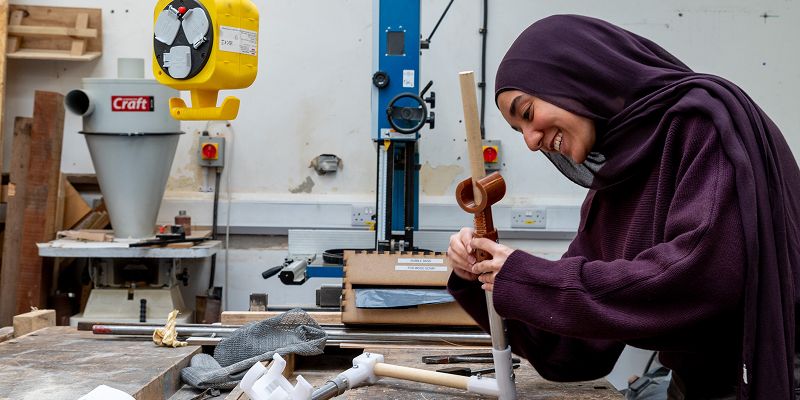 Fareda smiles as she connects two plastic pipes in a workshop setting
