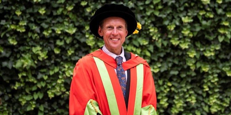 Jack Maitland in red and green graduation gowns.