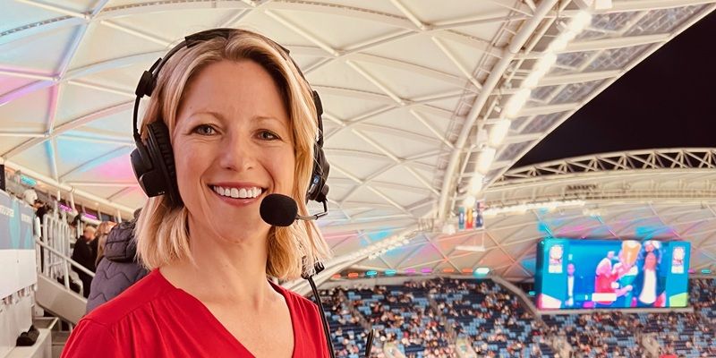 Jacqui Oatley at a sports event in a stadium full of people, wearing a commentator headset.