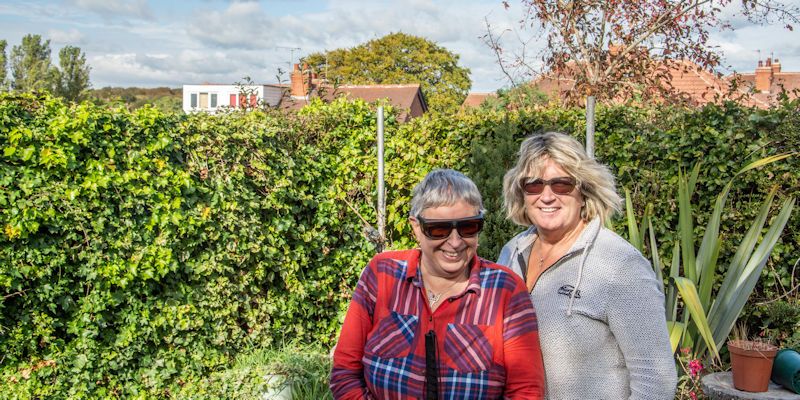 Sisters Jane and Helen Walker standing in a garden smiling