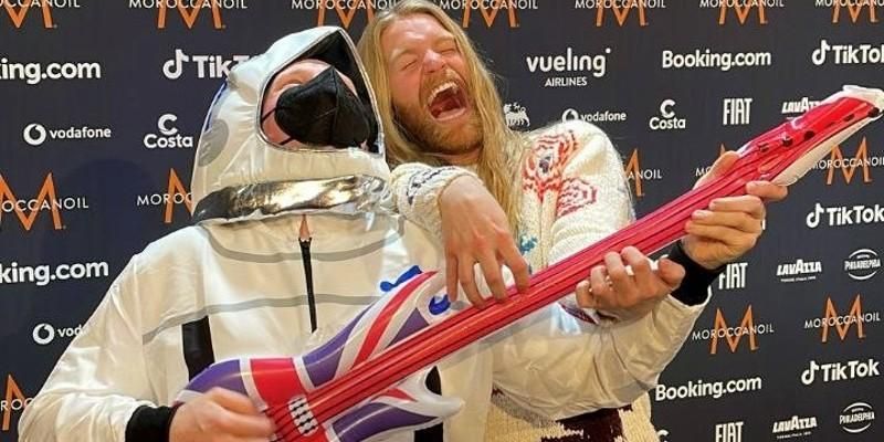 Joe Mason wears a fancy dress spacesuit and laughs as he plays an inflatable guitar alongside Sam Ryder