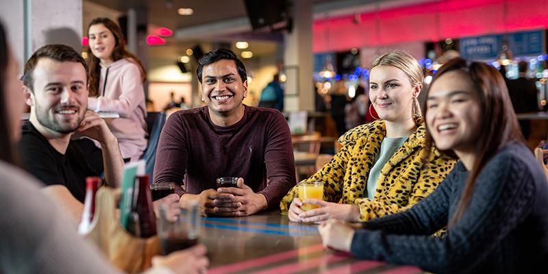 Keshav Bansal sitting at a table in a cafe with a group of friends.