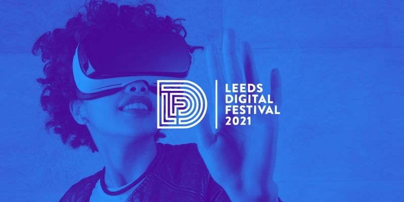 A person holds their hand up to the Leeds Digital Festival logo, whilst wearing a virtual reality headset
