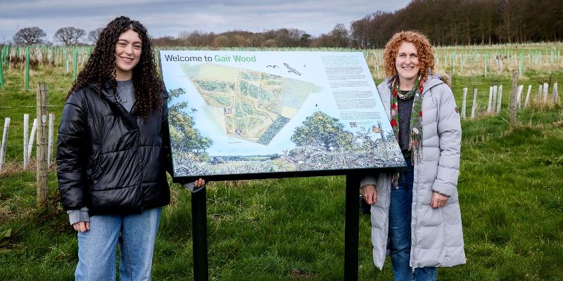 Leanne and Naomi stood next to a Gair Wood display board