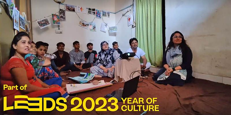 People seated in a room using a laptop and watching images from a projector. Text reads: Part of Leeds 2023 Year of Culture.
