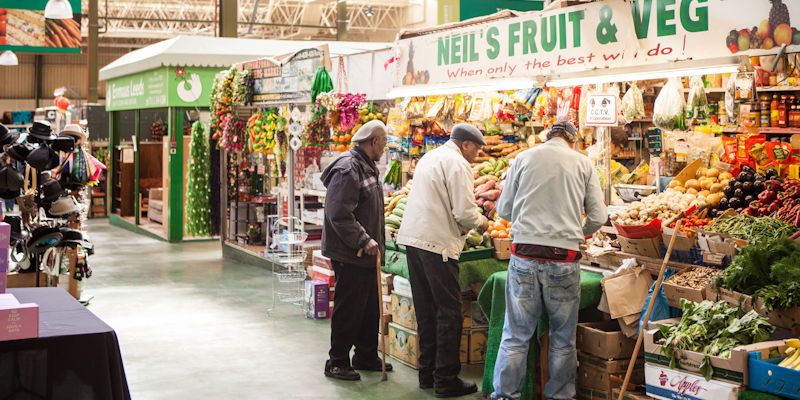 Customers selecting fresh fruit and vegetables at a Leeds market stall
