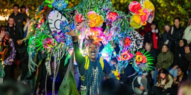 A performer wearing a colourful carnival costume dances at Light Night Leeds 2025.