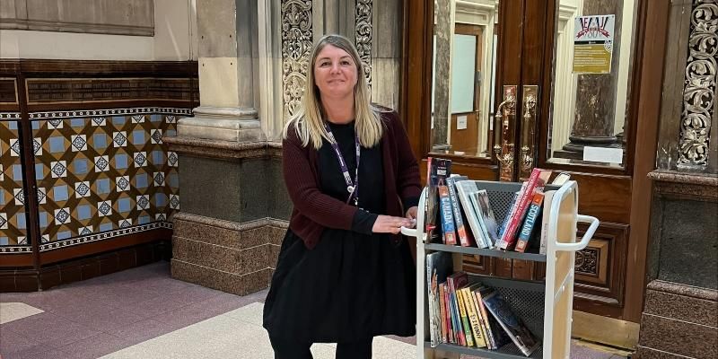 Lou is pictured with a trolley of books in Leeds City Library
