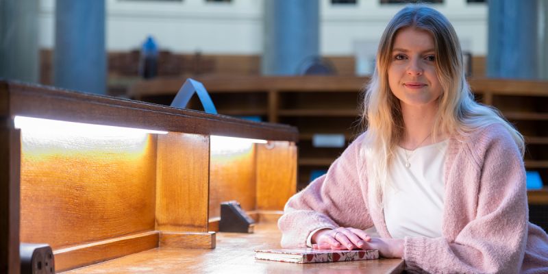 Eden Page sits at a desk in the Brotherton Library