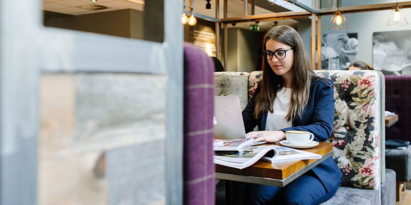 Student on a laptop in a comfortable, cafe environment.