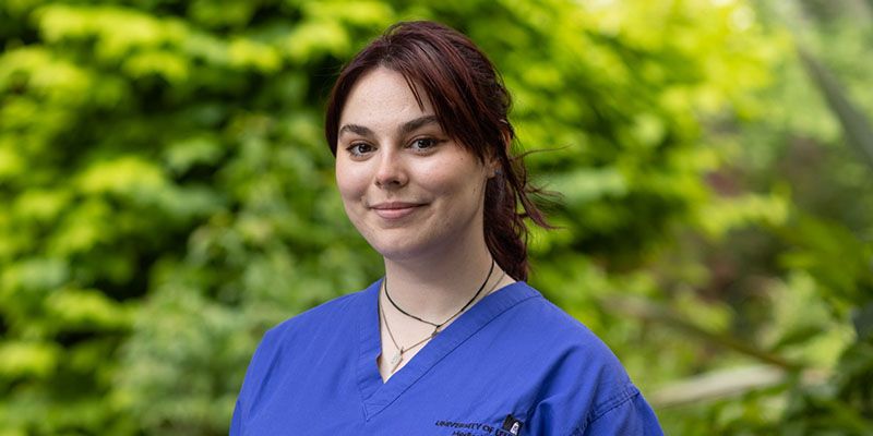 A smiling medical student wearing scrubs.