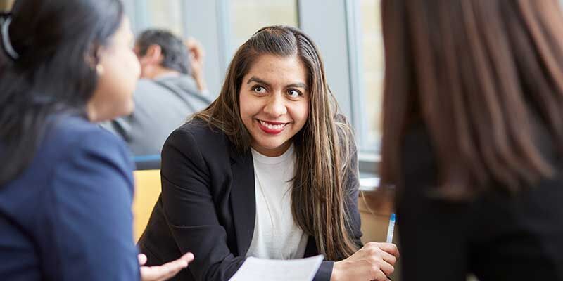 Three people having a meeting, one is smiling