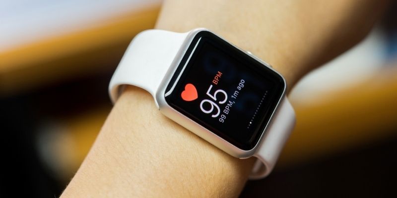 A smart watch on a person's wrist, with the display showing a heart rate of 95 beats per minute