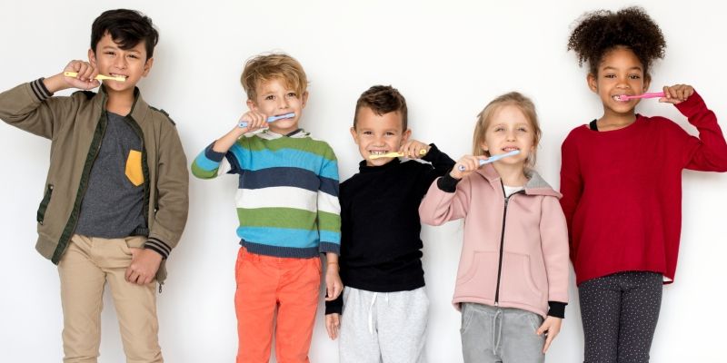 A group of five children brushing their teeth