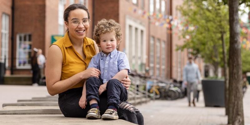 Natasha Pickard is sat with her son Oscar on some steps within the University campus.