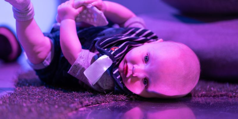 A baby lies on the floor and smiles