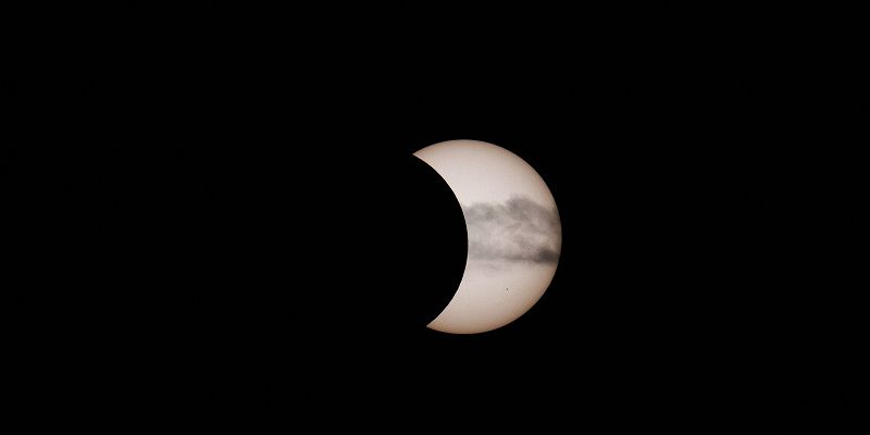 A partial solar eclipse over a silver moon