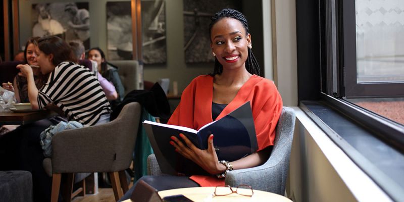 A Masters student sat in a cafe reading a book.