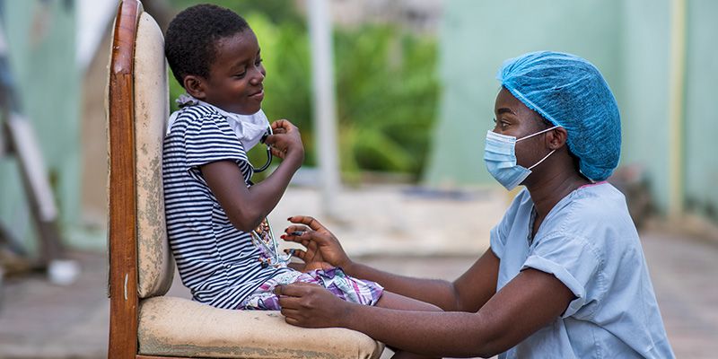 A young boy on a chair is being assessed by a healthcare professional.