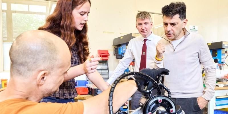 Ava Bird and Nick showing Alex Sobel MP the bike with Dr Anthony Herbert, listening behind them in the School of Mechanical engineering workshop.