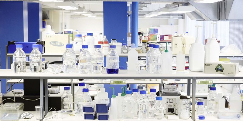 A view across a laboratory with a collection of bottle and vials closest to the camera