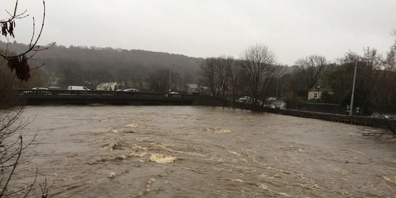 The image shows the River Aire on Boxing Day 2015 when the river was very high and flooded in Leeds. The water is extremely high and is almost coming over the top of a major bridge at Kirkstall.