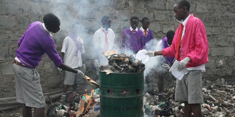 Children in Africa around an oil drum burning waste.
