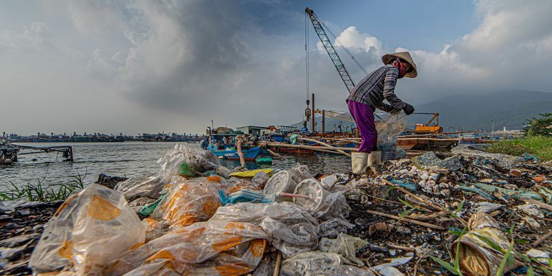 An informal waste worker combs through a pile of plastic