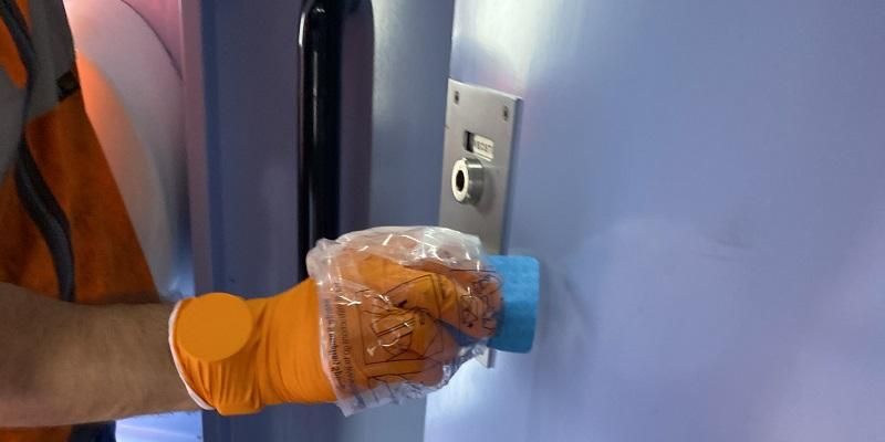 The image shows a swab being taken from a toilet door on a train