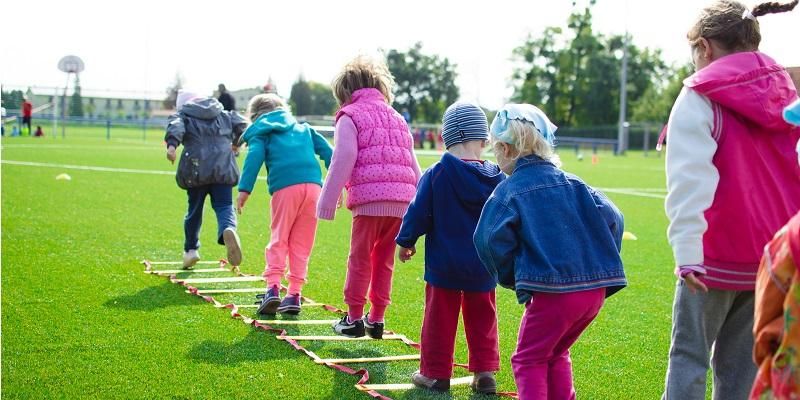 Picture shows a group of children jumping through squares laid out on the ground.