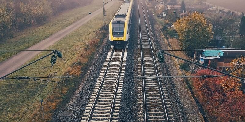 The image is taken from above a railway kline showing an approaching diesel train.