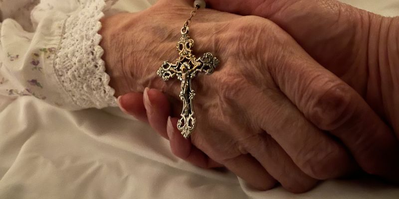 Sue Pavitt holds her mum Rosie Woollard's hand with a crucifix at the end of Rosie's life