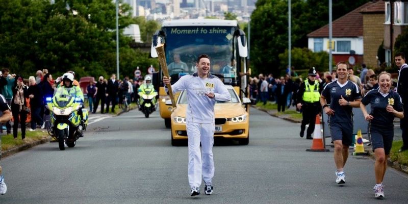 Stewart Ross walking up a Leeds road holding a torch