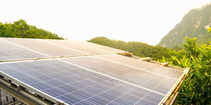 Solar panels in a rural setting, with mountains in the background.