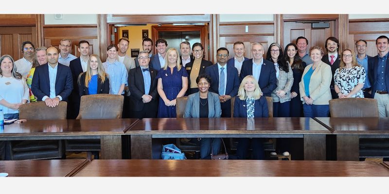 A large group of people sat and stood around a table.
