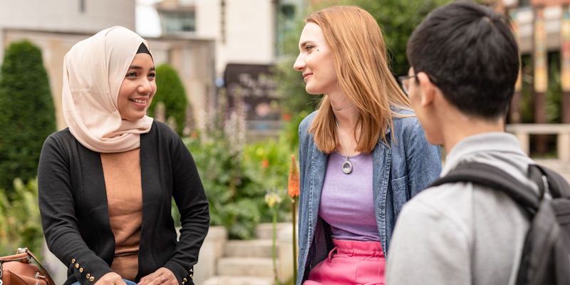 Students at the University of Leeds chat outside one of its buildings.