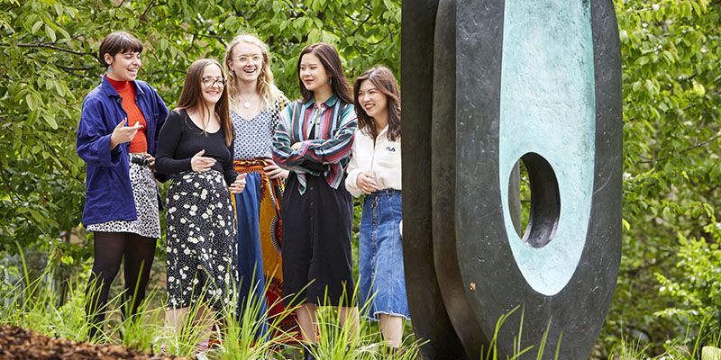Five students look at a Barbra Hepworth statue